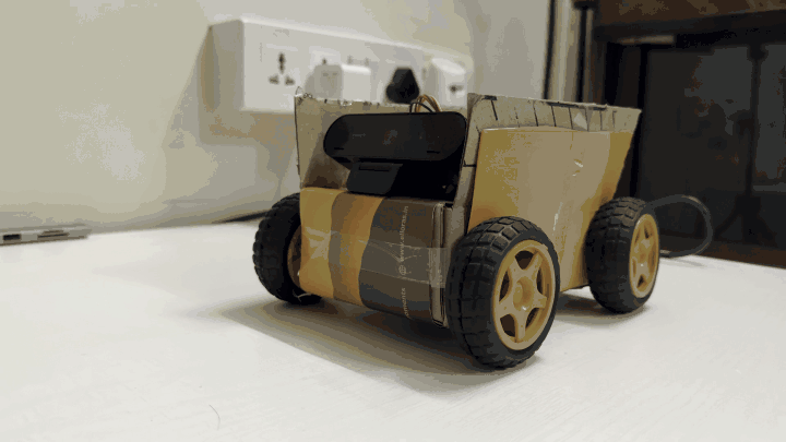 Looping clip of Boxtron's cardboard chassis slowly turning, showing the wheels, motor driver, and wiring from every side